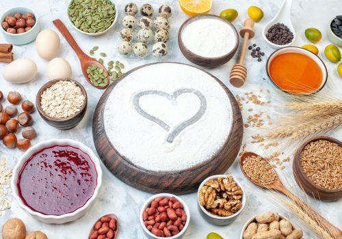 front-view-heart-shaped-flour-with-jelly-eggs-different-nuts-seeds-white-background-dough-sugar-cake-photo-nut-sweet-color-biscuit